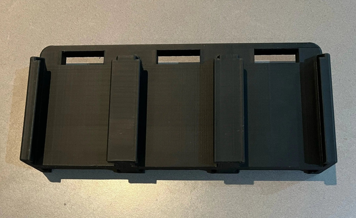 Top view of the Makita 6-Slot Battery Holder, highlighting the durable black construction and precise slots for safely holding up to six 18V batteries.