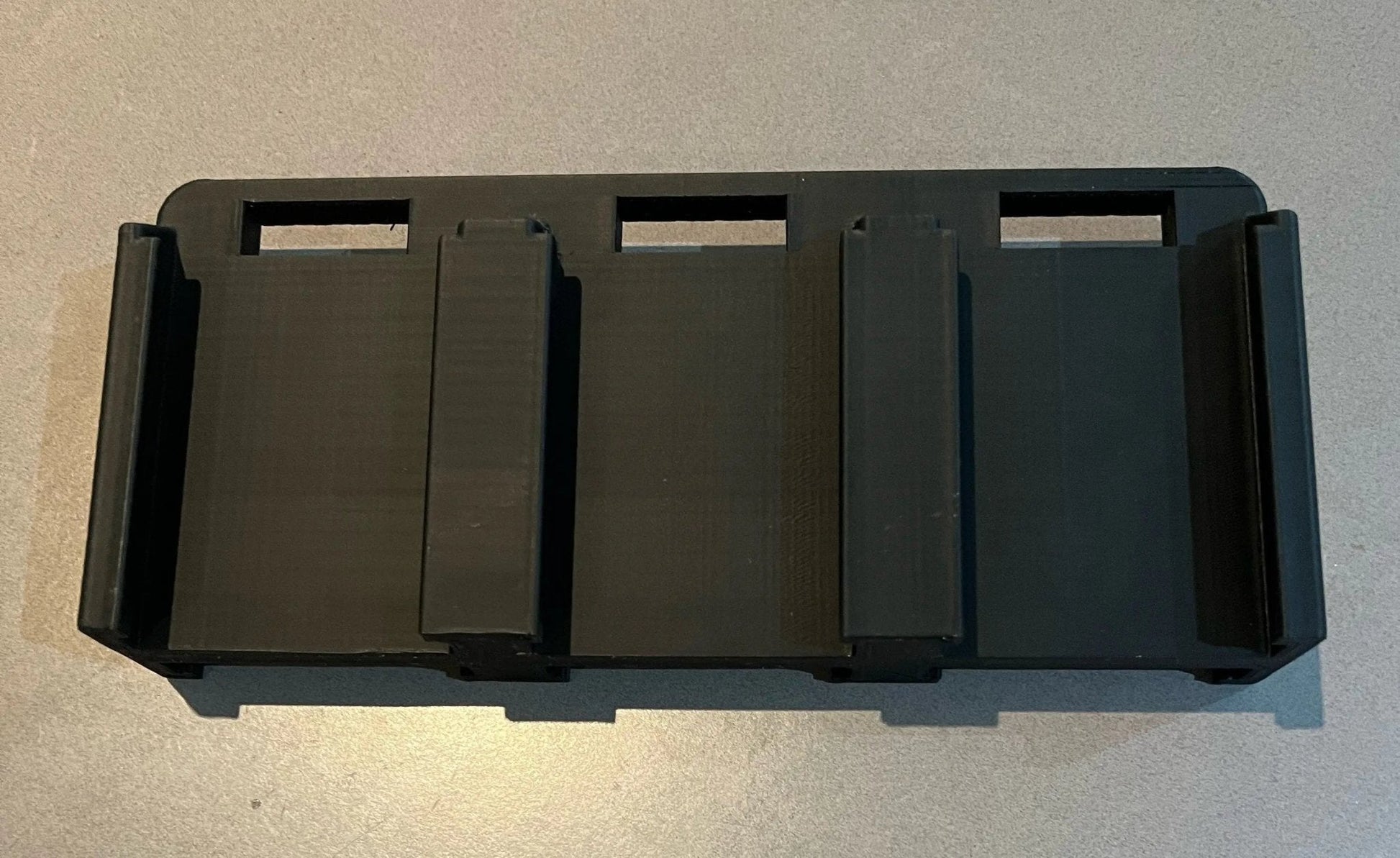 Top view of the Makita 6-Slot Battery Holder, highlighting the durable black construction and precise slots for safely holding up to six 18V batteries.