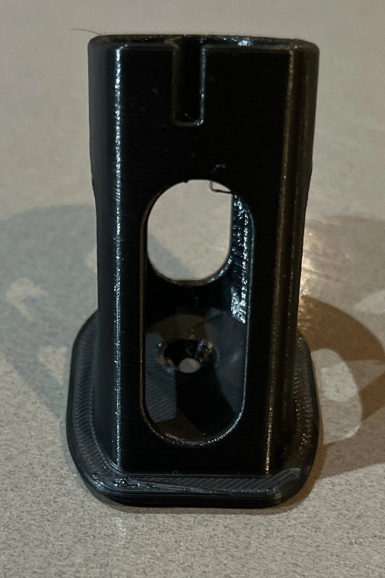 Vertical view of a Ryobi battery holder showcasing mounting holes and design, reinforcing the utility of the Ryobi 18V One+ Battery Holder – Wall-Mountable Organizer for Clean Garage.