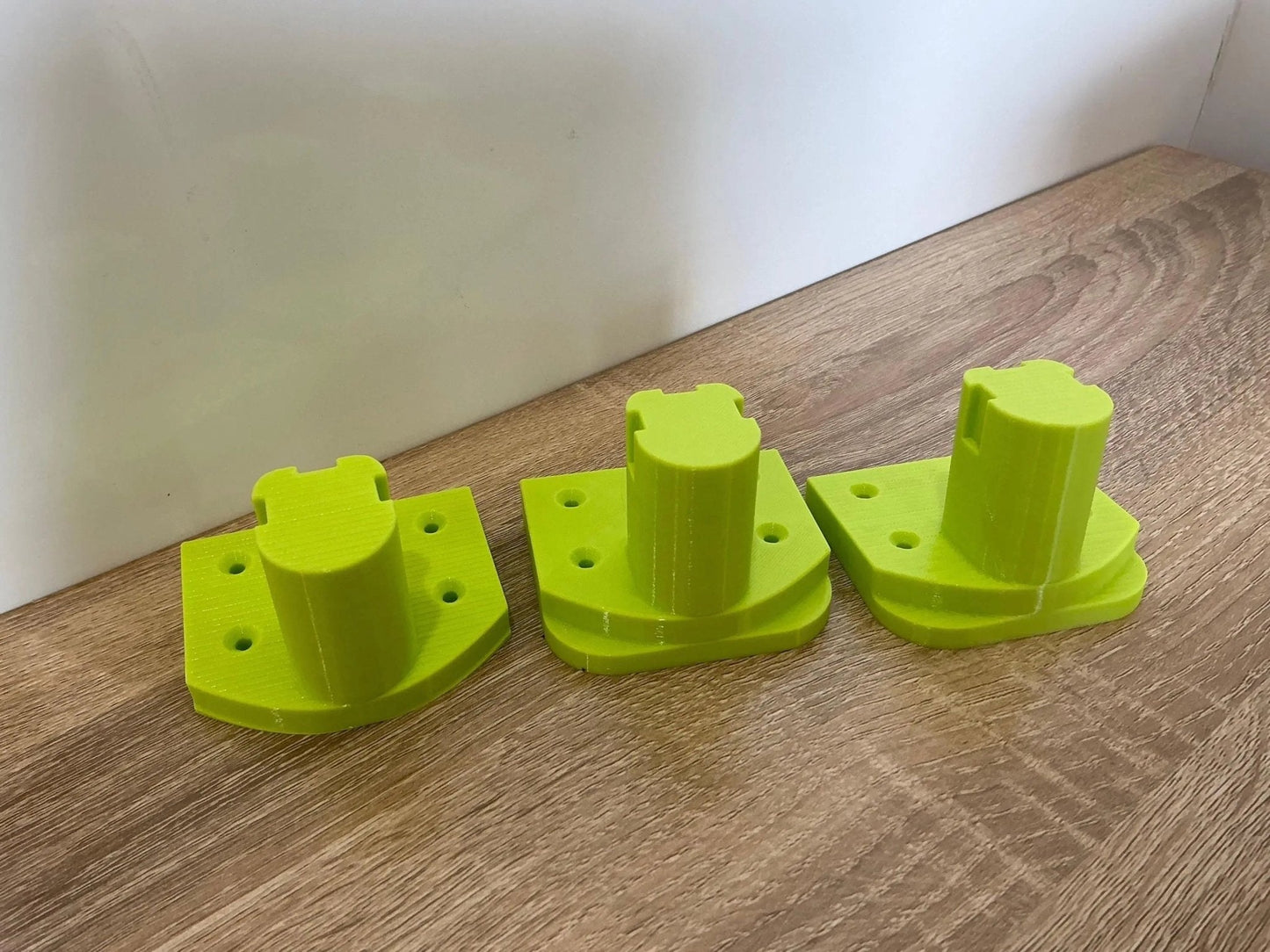 Ryobi Tool Mounts for Efficient Wall or Bench Storage – Organize Garage & Workshop. Three uniquely shaped tool mounts in bright yellow, showcasing their precision design for optimal tool storage.
