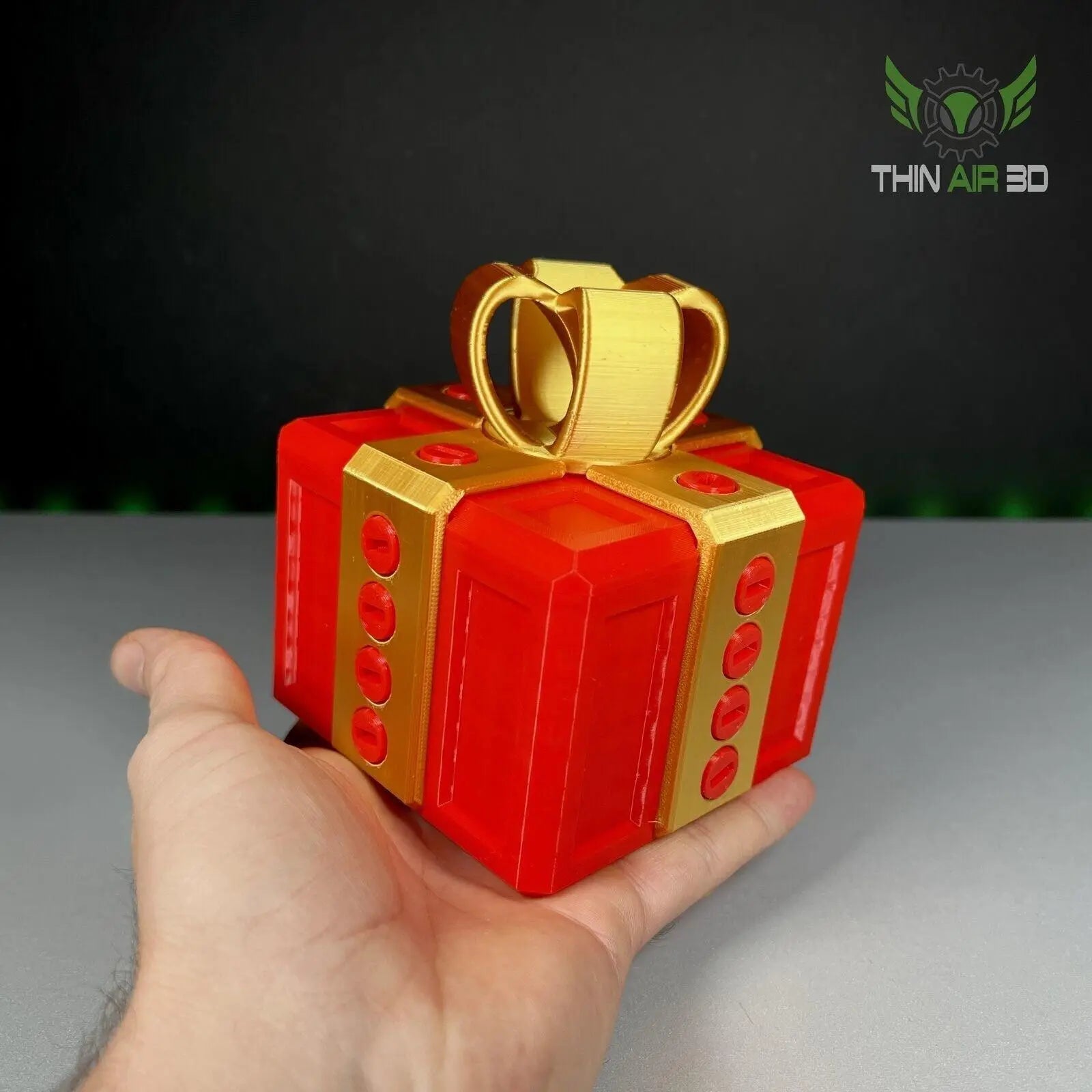 The Ultimate Challenge Gift Box held in a hand, showcasing the combination of red and gold colors and decorative bow, perfect for creative gifting.