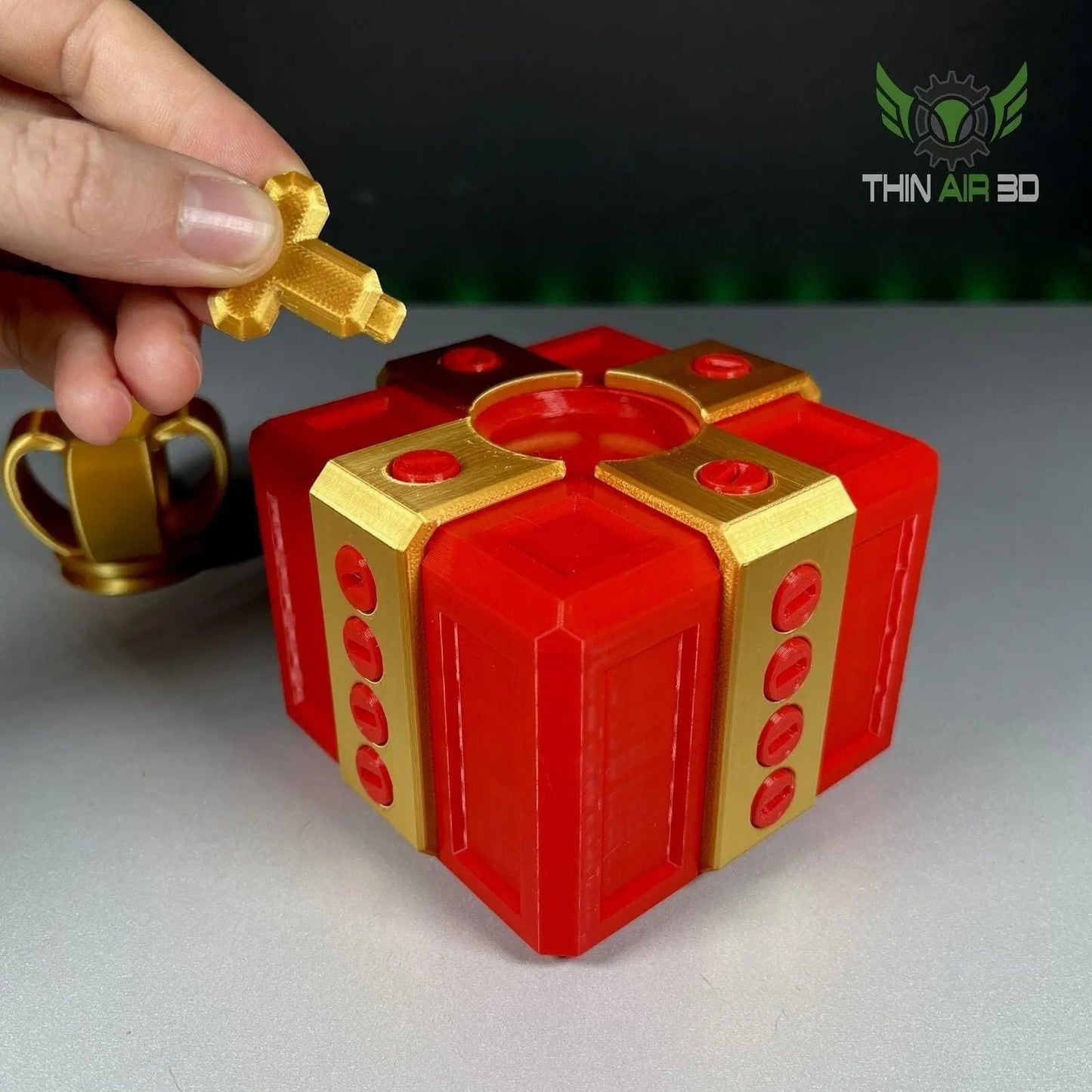 The Ultimate Challenge Gift Box featuring vibrant red and gold screws, showcasing a hand positioning a gold screw above the box.